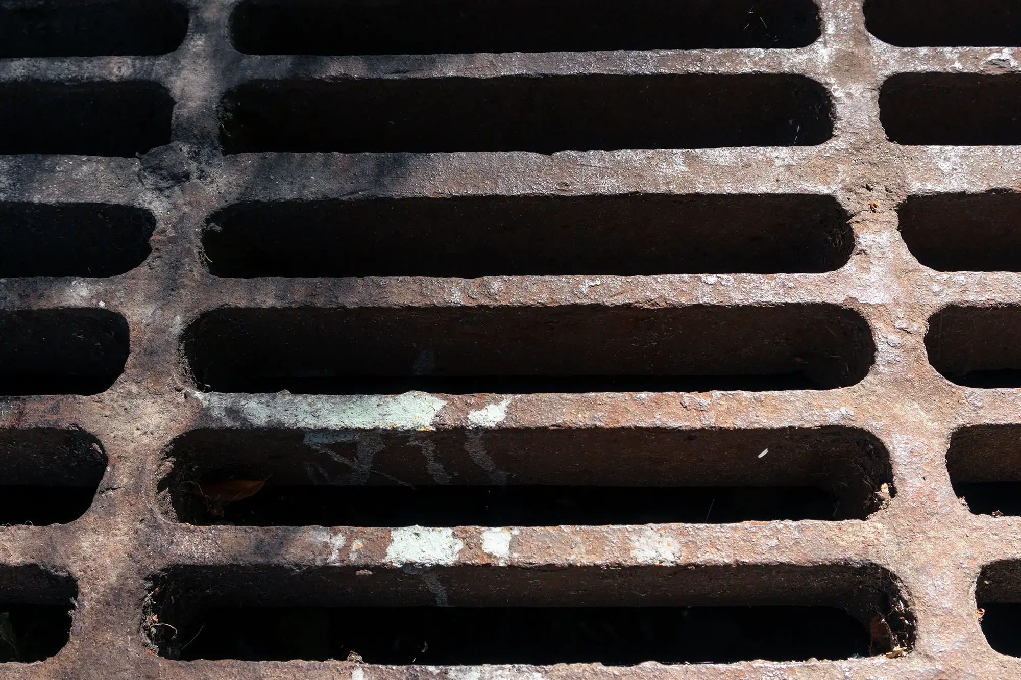 Rusty sewer drain grate. Metal sewer grate on asphalt road